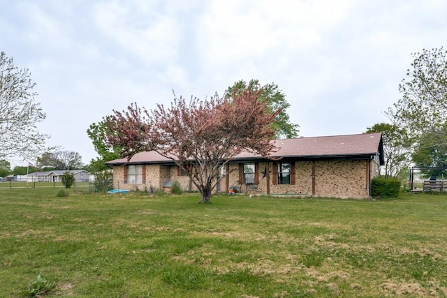 view of front facade with fence, a front lawn, and brick siding