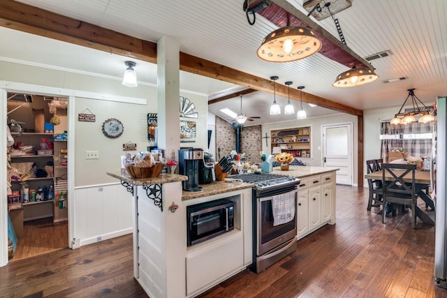 kitchen with a wood stove, dark wood-style flooring, black microwave, beamed ceiling, and gas stove