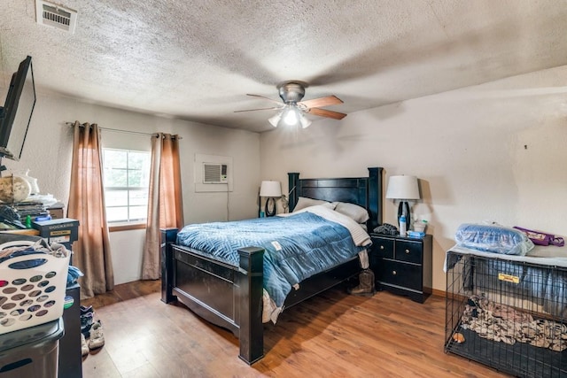 bedroom featuring a textured ceiling, visible vents, and wood finished floors