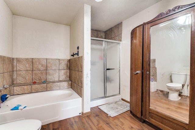 full bath with a bath, a shower stall, toilet, and wood finished floors