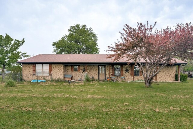 rear view of property featuring a yard and brick siding