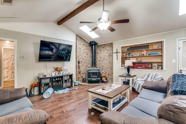 living room with vaulted ceiling with beams, ceiling fan, a wood stove, and wood finished floors