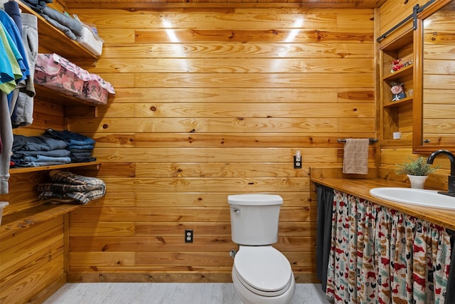 bathroom with toilet, wood walls, vanity, and wood finished floors
