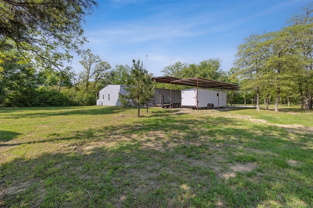view of yard featuring a pole building, an outbuilding, and a carport