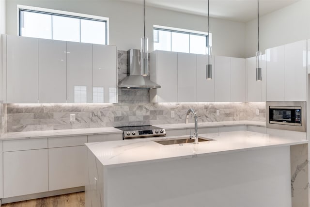 1775 Novela Way, Dallas, TX 75215 - kitchen with wall chimney range hood, a sink, appliances with stainless steel finishes, modern cabinets, and a center island with sink