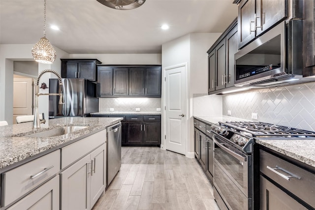 736 Wilmott Ter, Fort Worth, TX 76247 - kitchen featuring appliances with stainless steel finishes, a sink, light wood-style floors, backsplash, and light stone counters