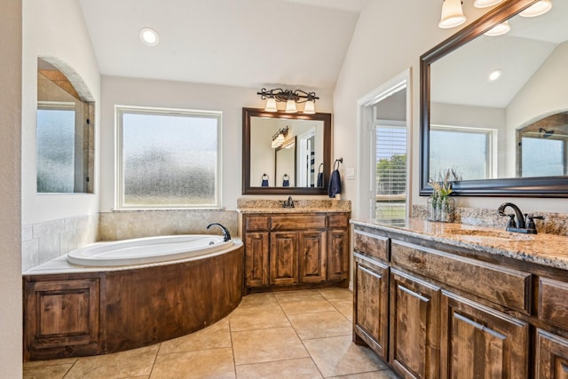 bathroom with a bath, vaulted ceiling, two vanities, and a sink
