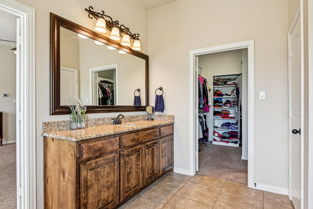 bathroom featuring baseboards, a spacious closet, tile patterned floors, and vanity
