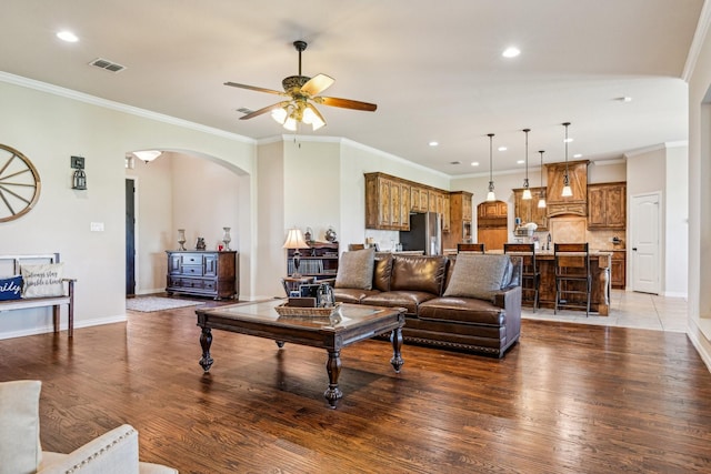 living room featuring arched walkways, wood finished floors, visible vents, and ceiling fan