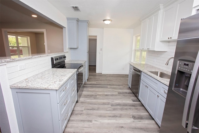 kitchen with decorative backsplash, stainless steel appliances, visible vents, and a sink