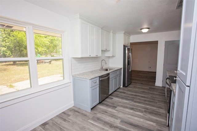kitchen featuring a sink, visible vents, backsplash, wood finished floors, and appliances with stainless steel finishes