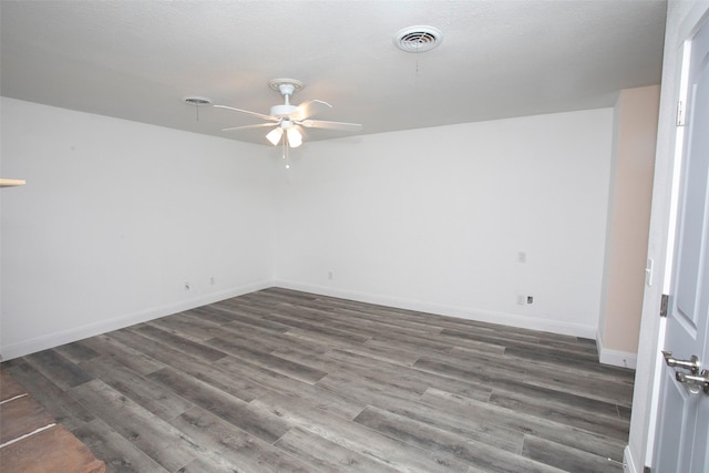 spare room with baseboards, a ceiling fan, visible vents, and dark wood finished floors