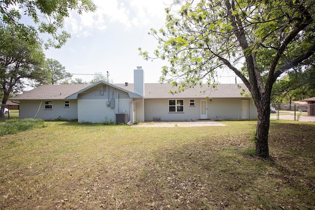 rear view of property with a chimney, a yard, cooling unit, and a patio