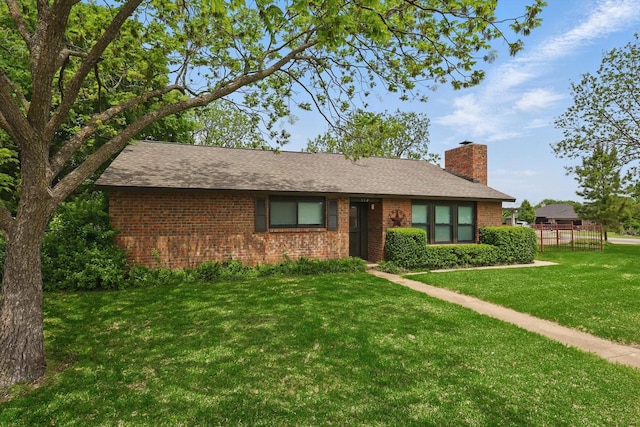 ranch-style home with brick siding, a chimney, a shingled roof, and a front lawn