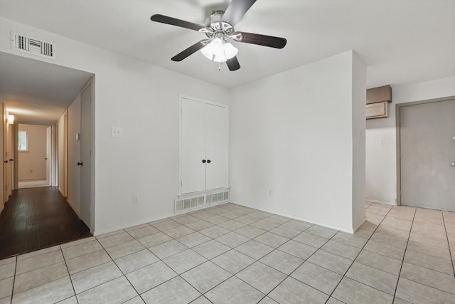 empty room featuring visible vents, ceiling fan, light tile patterned floors, and an AC wall unit