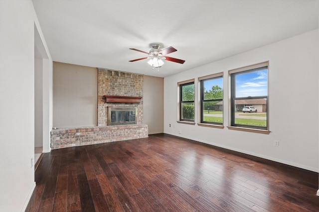 unfurnished living room featuring wood-type flooring, a ceiling fan, baseboards, and a brick fireplace