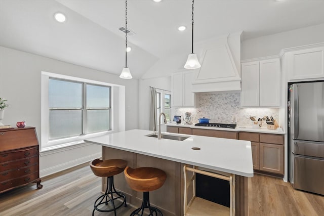 kitchen featuring light wood finished floors, a sink, freestanding refrigerator, gas stovetop, and custom exhaust hood