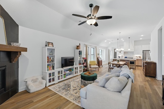 living room with recessed lighting, light wood-style floors, vaulted ceiling, and ceiling fan with notable chandelier