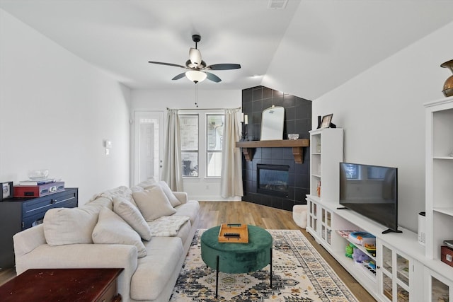 living area with lofted ceiling, wood finished floors, visible vents, a ceiling fan, and a fireplace