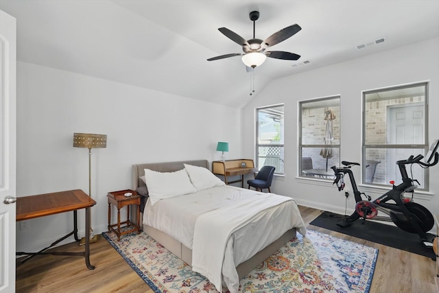 bedroom featuring lofted ceiling, a ceiling fan, wood finished floors, and visible vents