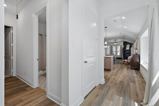 hallway featuring recessed lighting, lofted ceiling, visible vents, baseboards, and light wood-style flooring