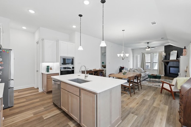 kitchen featuring vaulted ceiling, a sink, light wood-style floors, appliances with stainless steel finishes, and open floor plan