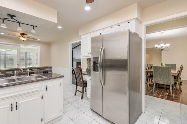 kitchen with white cabinets, marble finish floor, a sink, stainless steel refrigerator with ice dispenser, and ceiling fan with notable chandelier
