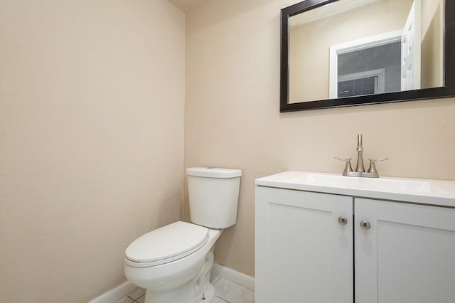 half bathroom featuring toilet, vanity, and baseboards