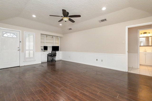 unfurnished living room with wainscoting, visible vents, a textured ceiling, and ceiling fan