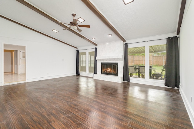 unfurnished living room featuring a wealth of natural light, vaulted ceiling with beams, a fireplace, and ceiling fan