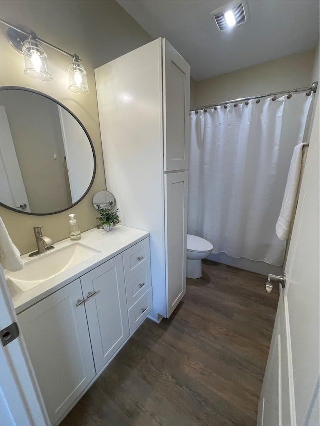 bathroom with visible vents, wood finished floors, toilet, and vanity