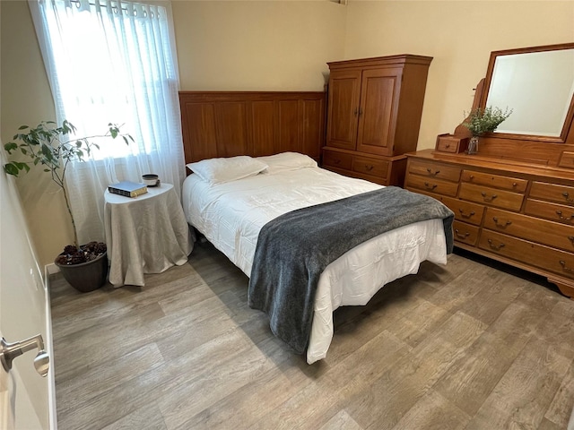 bedroom with wainscoting and light wood finished floors