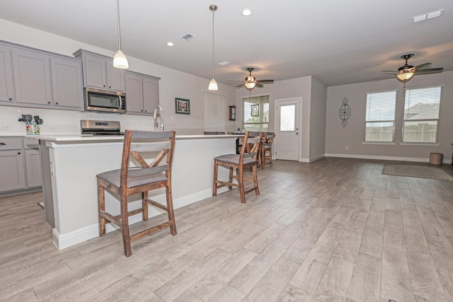 4125 Stockman Dr, Krum, TX 76249 - kitchen featuring stainless steel appliances, gray cabinets, a ceiling fan, light wood-style flooring, and recessed lighting