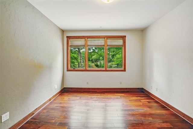 unfurnished room with wood-type flooring and baseboards