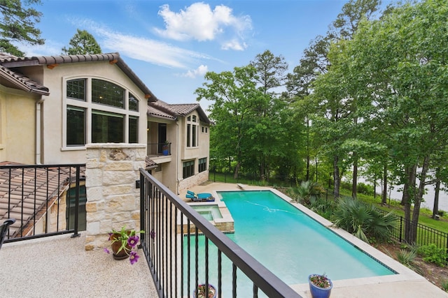view of swimming pool featuring fence, a diving board, a pool with connected hot tub, and a patio area