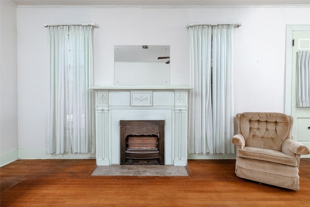 living area with wood finished floors and ornamental molding