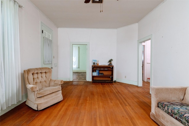 sitting room featuring ceiling fan, ornamental molding, and light wood-type flooring