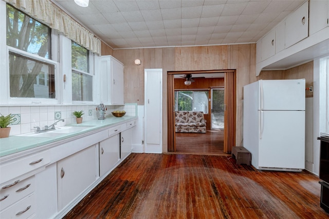 kitchen with light countertops, freestanding refrigerator, a sink, and dark wood-type flooring