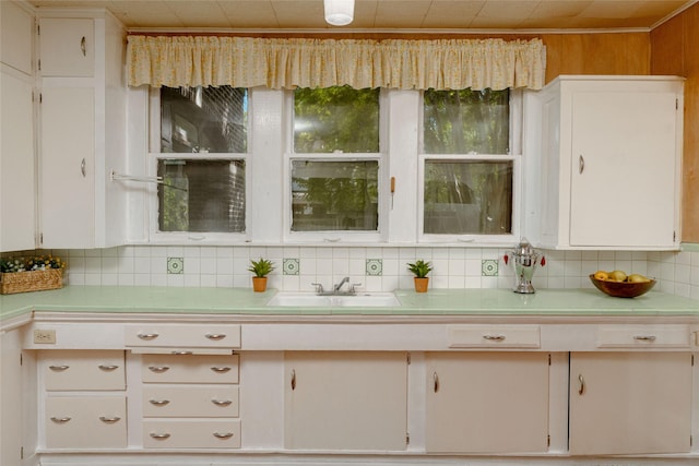 kitchen featuring white cabinets, backsplash, tile counters, and a sink