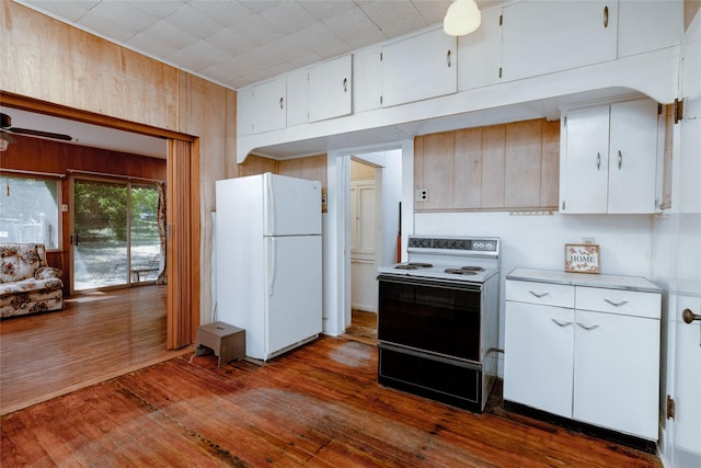 kitchen with dark wood-style floors, light countertops, wooden walls, electric stove, and freestanding refrigerator
