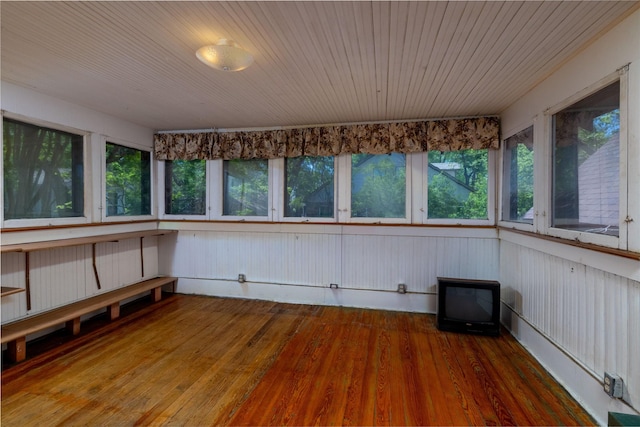unfurnished sunroom featuring wooden ceiling, wood finished floors, and plenty of natural light