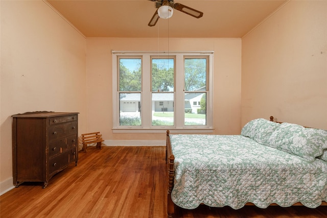 bedroom featuring baseboards, ornamental molding, and light wood finished floors