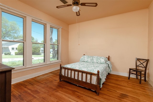 bedroom with crown molding, light wood finished floors, baseboards, and ceiling fan