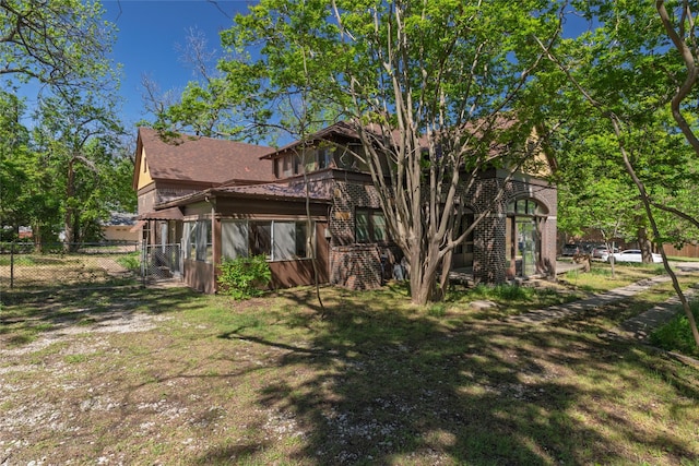 view of side of home with fence, brick siding, roof with shingles, and a gate