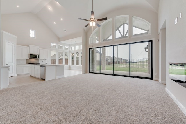 1006 Cascading Creek Dr, Rockwall, TX 75087 - unfurnished living room featuring high vaulted ceiling, light colored carpet, ceiling fan, baseboards, and a sink