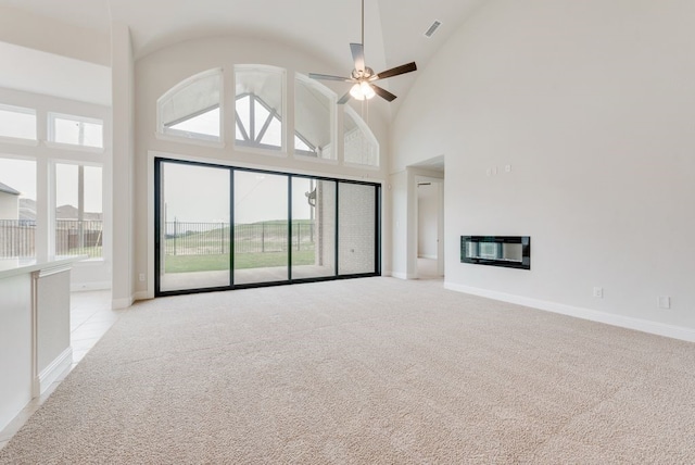 1006 Cascading Creek Dr, Rockwall, TX 75087 - unfurnished living room with light carpet, baseboards, a glass covered fireplace, a ceiling fan, and high vaulted ceiling