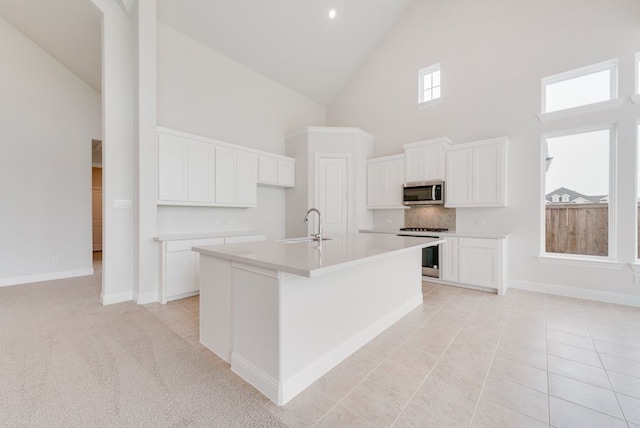 1006 Cascading Creek Dr, Rockwall, TX 75087 - kitchen featuring range, high vaulted ceiling, stainless steel microwave, an island with sink, and a sink