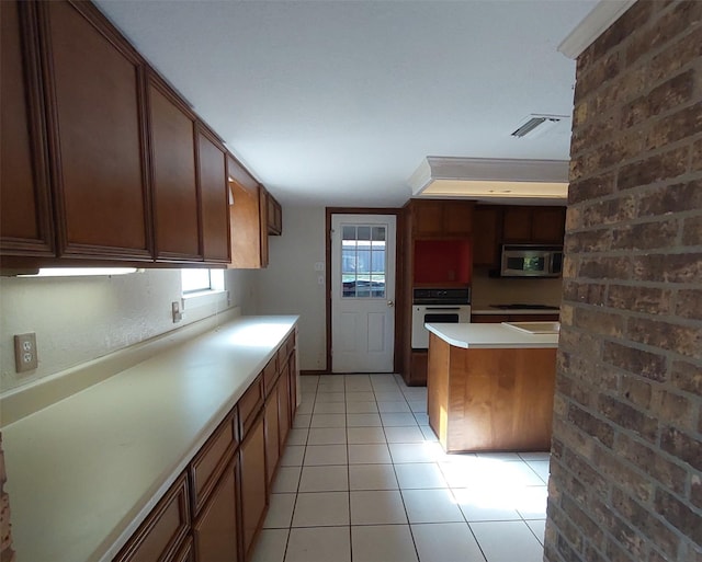 kitchen with light countertops, visible vents, light tile patterned floors, stainless steel microwave, and white oven