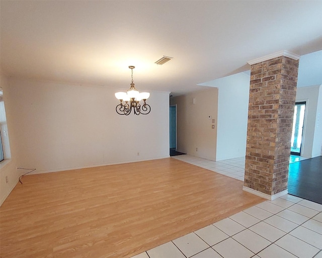 empty room featuring light wood-type flooring, visible vents, ornate columns, and an inviting chandelier