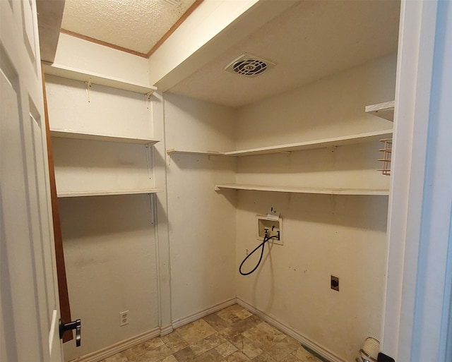 clothes washing area featuring hookup for a washing machine, electric dryer hookup, laundry area, stone finish floor, and visible vents